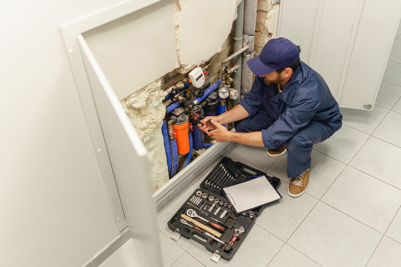 Handyman in uniform repairing water supply system at home uses an adjustable wrench