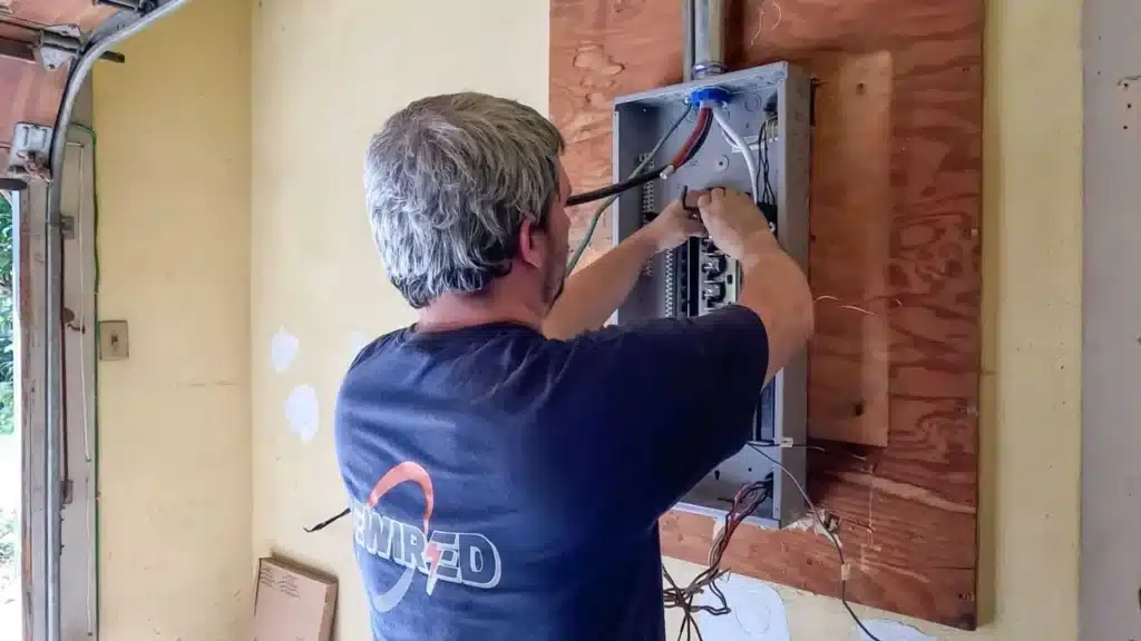 Electrician working on an electrical panel upgrade, demonstrating the installation process for increased amperage to support modern equipment in a Central Iowa home.