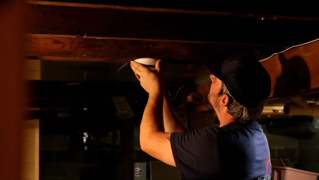Electrician inspecting a home's circuit breaker panel at night