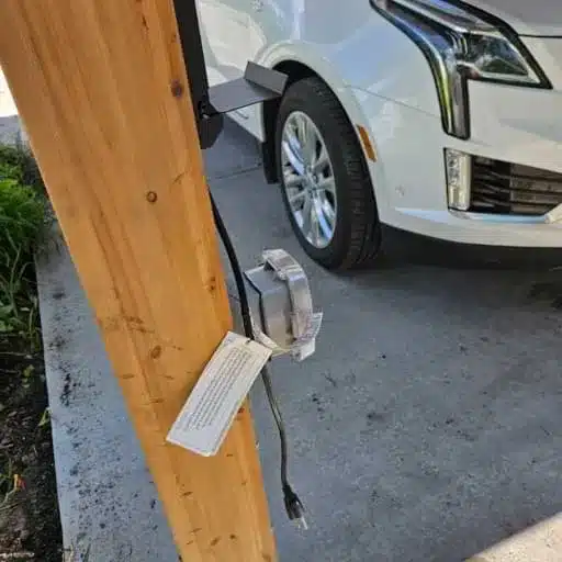 Service drop and weatherhead connected to a white vehicle, with visible electrical components and potential signs of wear or damage, relevant to outdoor electrical issues and safety inspections.
