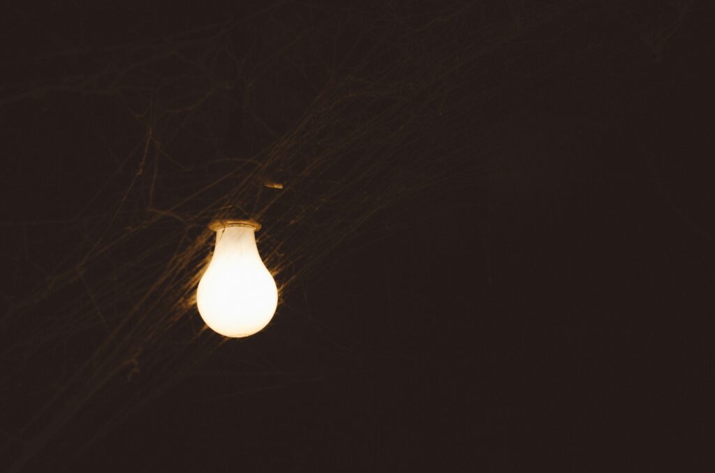 Light bulb hanging in darkness, symbolizing flickering lights and electrical issues, relevant to troubleshooting and surge protection discussions.