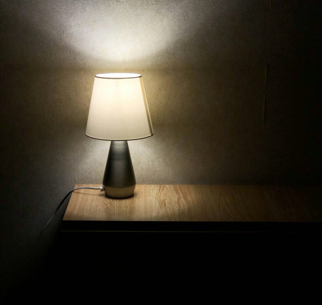 Lamp on wooden table casting warm light, illustrating potential flickering issue related to dimmer switches and LED compatibility.
