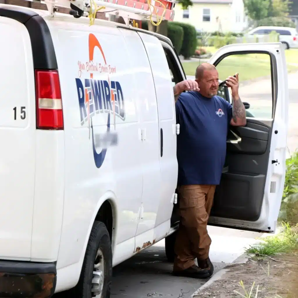 Electrician standing next to a Rewired Iowa service van, preparing for emergency electrical service call.