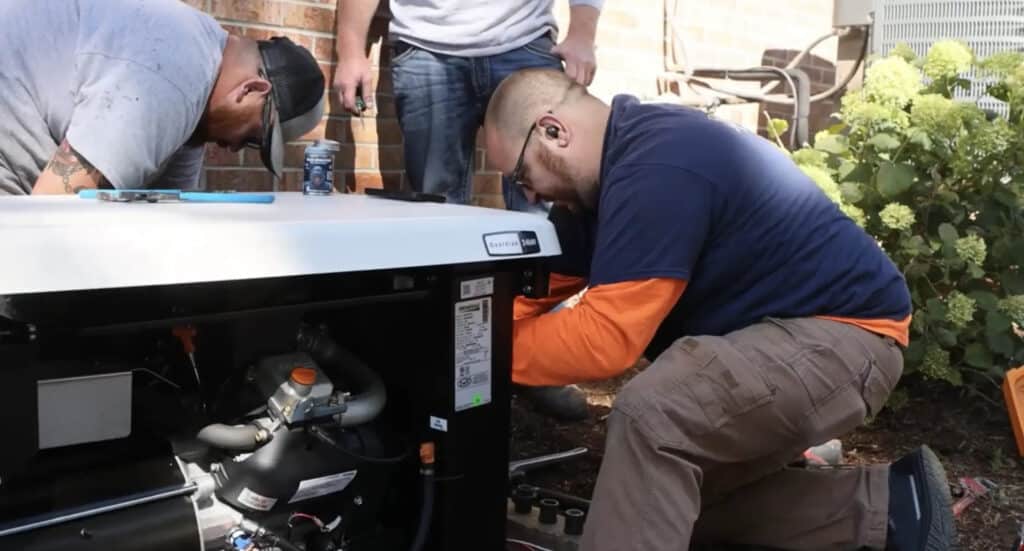 Two men working on a generator outdoors, with tools and equipment nearby