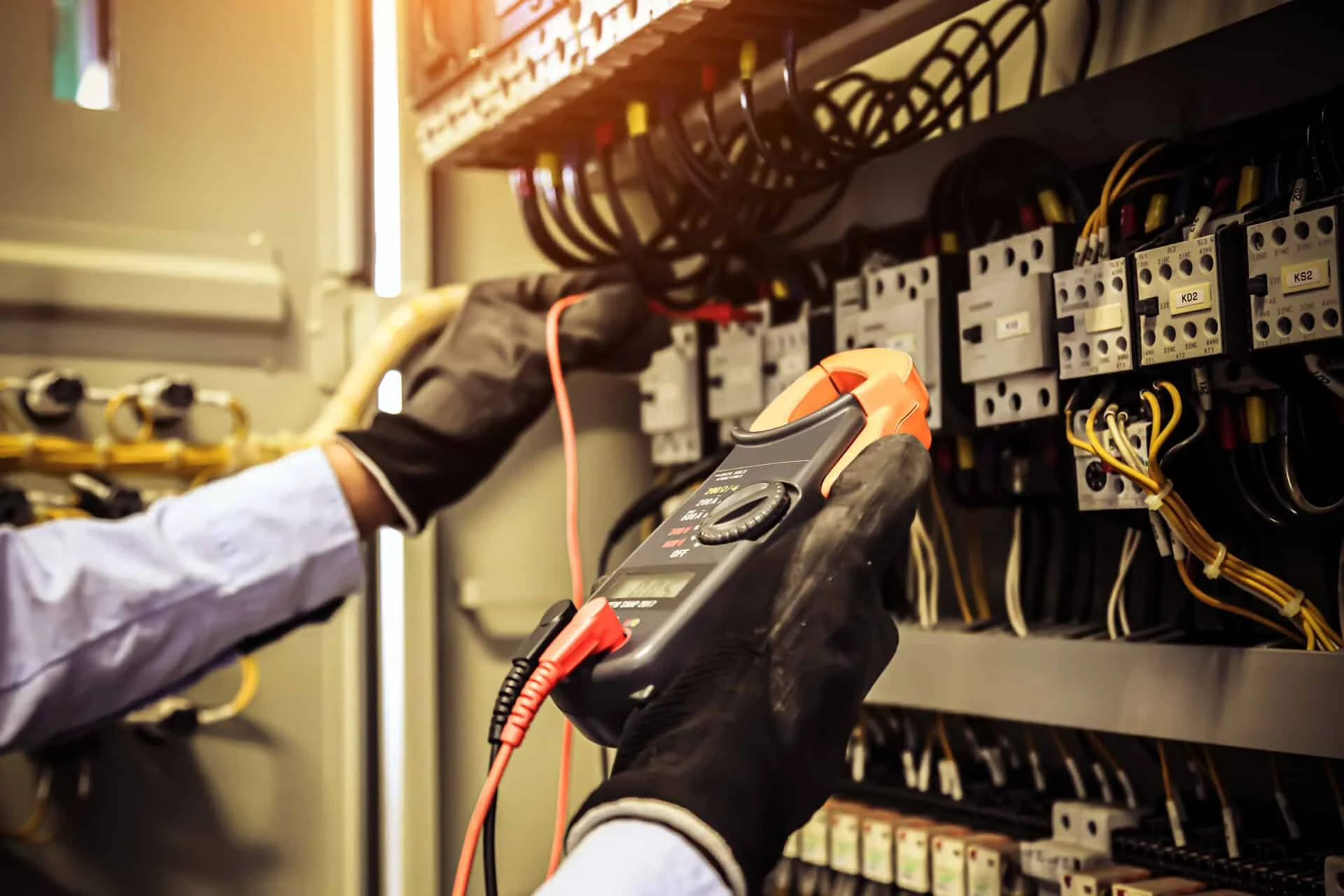 Electrician using a multimeter to inspect electrical panel in Ankeny IA, emphasizing expert electrical repairs and maintenance services.