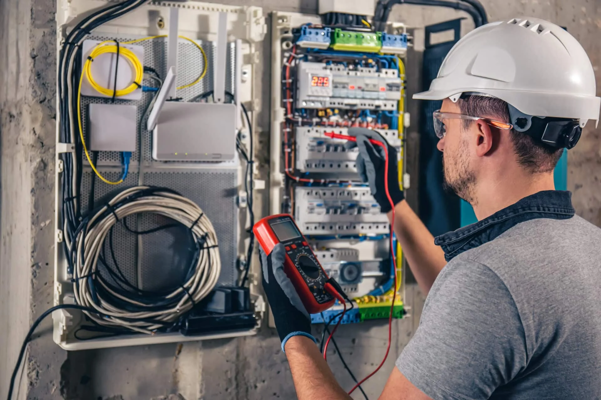 Electrician using a multimeter to inspect electrical panel, showcasing professional electrical renovation services in Ankeny, IA.